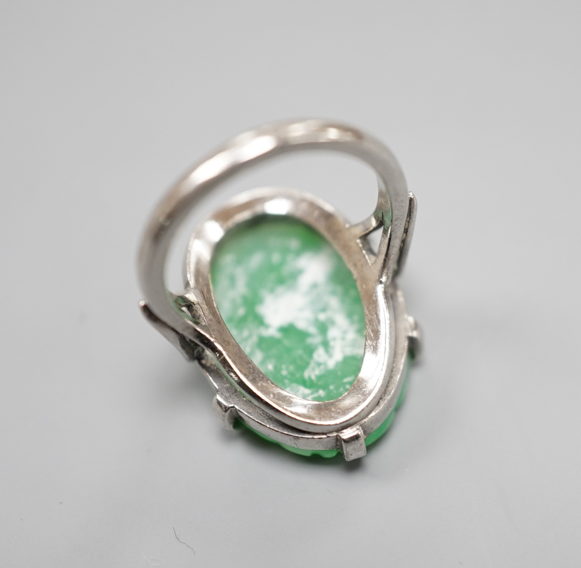 A white metal and oval jade set ring, carved with fruit, size F, gross weight 6.3 grams.
